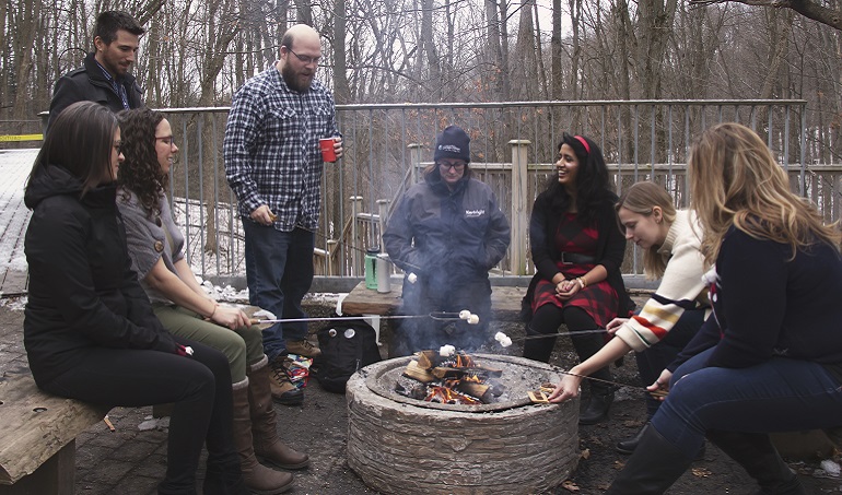 TRCA staff members toast marshmallows over campfire at annual pancake breakfast