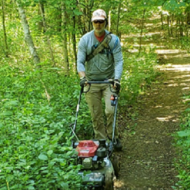 A Green Durham Association volunteer keeps the trail width clear of vegetation by mowing the trail edge in the East Duffins Headwaters Properties in Uxbridge