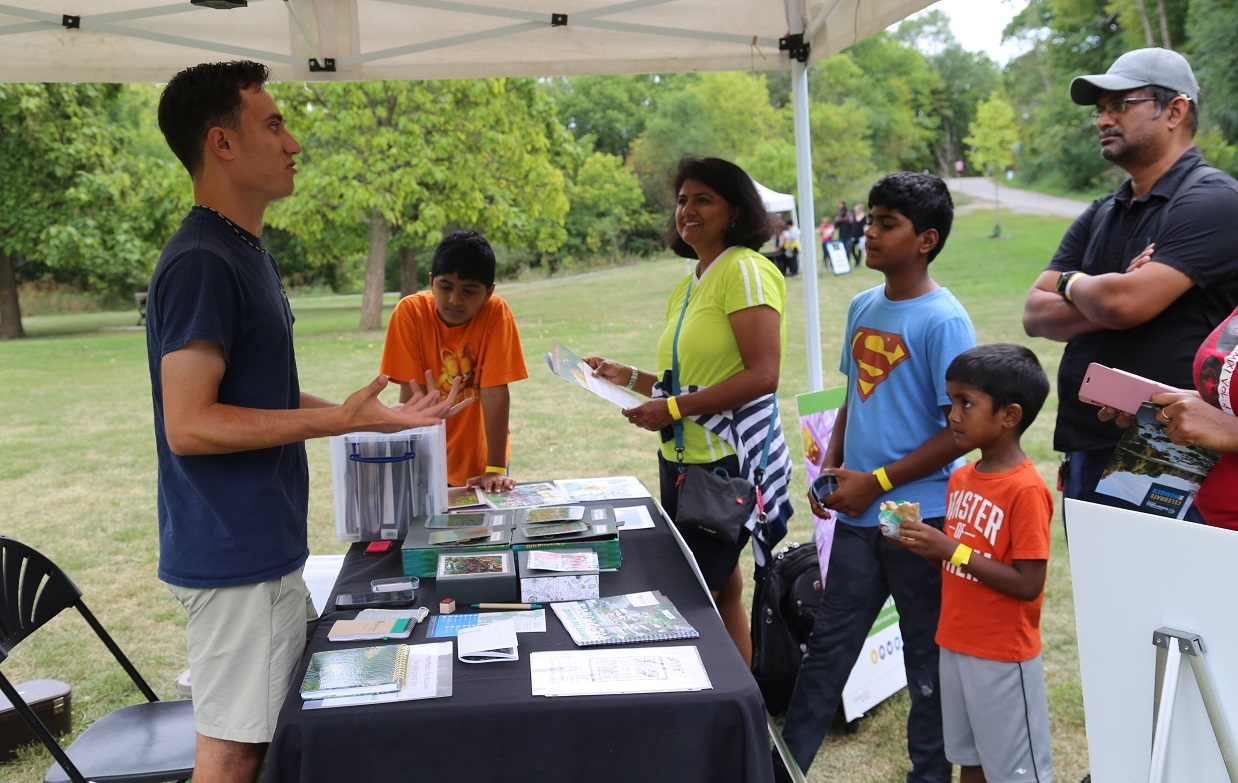 volunteer greets visitors to educational station at TRCA Celebrate the Humber event